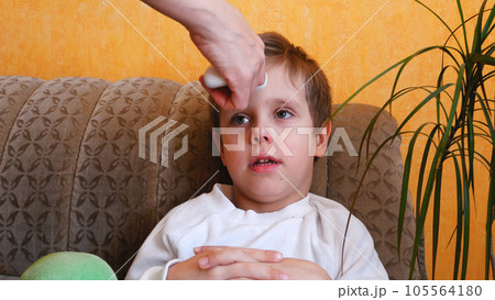 A woman's hand with an electronic thermometer measures the temperature of a child 105564180