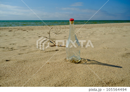 White glass bottle on the sandy beach in the sun, sea or ocean waste concept. Baltic Sea Latvia White glass bottle on the sandy beach in the sun, sea or ocean waste concept. Baltic Sea Latvia 105564494