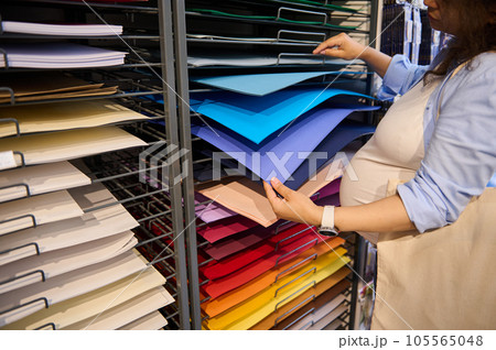 Multicolored cardboard sheets or design paper of vibrant spectrum in artist designer's hands selecting paper in art shop 105565048