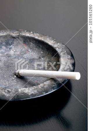 A lit cigarette and an ashtray closeup A lit cigarette and an ashtray closeup 105565260