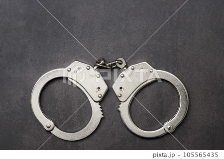 The metal handcuffs on black background. Handcuff or shackle. Police handcuffs The metal handcuffs on black background. Handcuff or shackle. Police handcuffs 105565435
