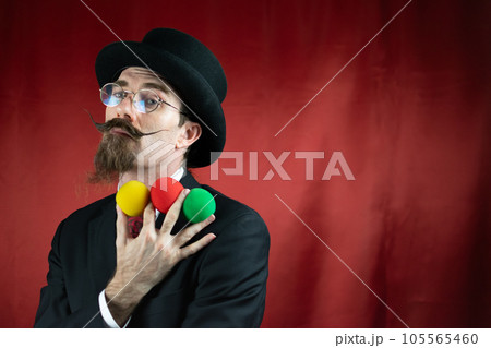 Vintage Caucasian Magician with top hat, glasses and mustache with colored balls 105565460