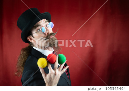 Vintage Caucasian Magician with top hat, glasses and mustache with colored balls Vintage Caucasian Magician with top hat, glasses and mustache with colored balls 105565494