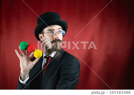 Vintage Caucasian Magician with top hat, glasses and mustache with colored balls 105565496