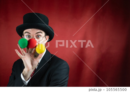 Vintage Caucasian Magician with top hat, glasses and mustache with colored balls 105565500