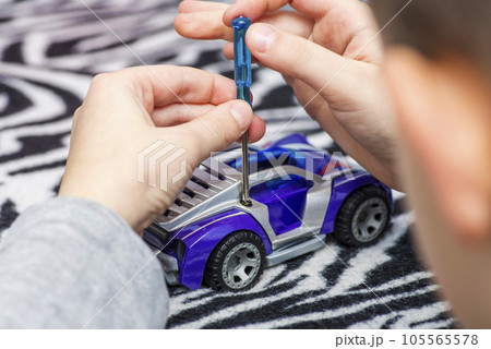 Small child boy holding screwdriver, fixing broken toy. 105565578