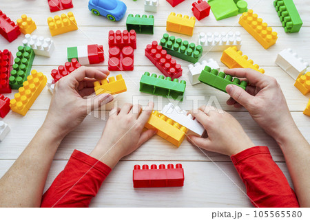 Top view on childs and fathers hands playing with colorful plastic bricks. 105565580