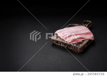 Fresh raw bacon cut into slices with salt, spices and herbs 105565720
