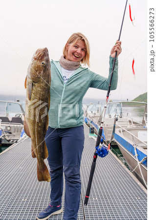 Happy Fisherwoman holding big arctic cod. Norway happy fishing. Woman with cod fish in hands 105566273