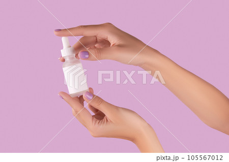 Womans hand holding dropper with serum on pastel lavender background 105567012