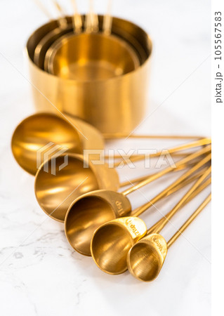 Close-up view. Cupper measuring cups and spoons for baking on a marble countertop. Close-up view. Cupper measuring cups and spoons for baking on a marble countertop. 105567583