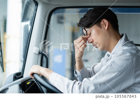 トラックを運転して疲れを感じる若い男性ドライバー トラックを運転して疲れを感じる若い男性ドライバー 105567843