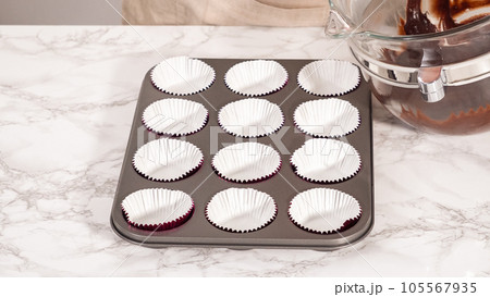 Step by step. Baking chocolate cupcakes. Scooping chocolate cupcake batter into a cupcake pan. 105567935