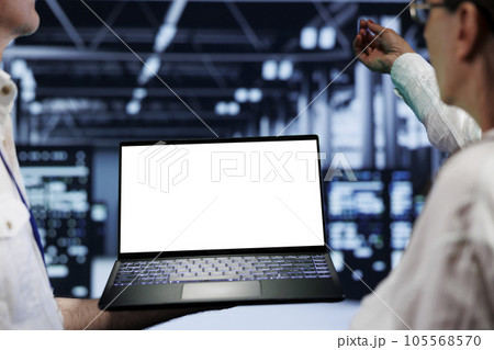 Close up shot of mock up laptop used by professional mechanic in data center server room delivering massive computing power, capable of processing and storing vast amounts of datasets 105568570