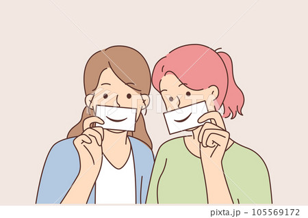 Two women with fake smiles hold papers with drawn emotions and pretend to be happy Two women with fake smiles hold papers with drawn emotions and pretend to be happy 105569172