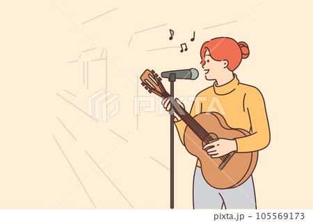 Woman street musician plays guitar and sings standing on sidewalk with microphone 105569173