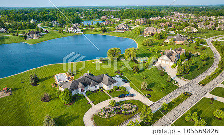 Textured techno road through rich neighborhood property fresh cut grass homes near pond aerial 105569826