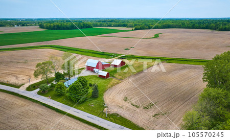 Aerial red barn, farmhouse empty tilled fields forests, green pasture, real estate property asset 105570245