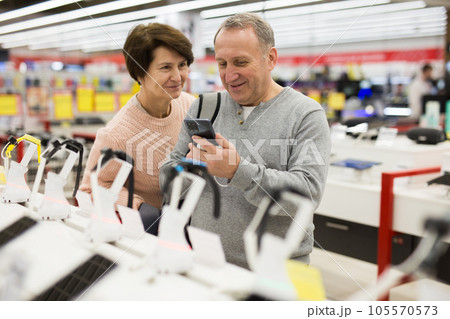 Middle aged wife and husband picking new smartphone in electronic store 105570573