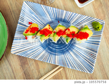 Uramaki - Dragon sushi roll with salmon and mango, tropical flavor. Uramaki - Dragon sushi roll with salmon and mango, tropical flavor. 105570758