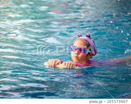 Asian child or kid girl wearing swimming suit to learning on swimming pool , learn and training swim on kick board Asian child or kid girl wearing swimming suit to learning on swimming pool , learn and training swim on kick board 105573007
