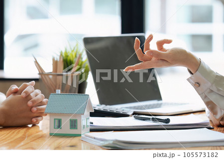 Real estate broker agent presenting and consult to customer to decision making sign insurance form agreement, home model, concerning mortgage loan offer for and house insurance. 105573182