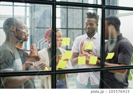 a team of young designers sticking notes on glass in a modern office 105576415
