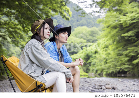 椅子に座って二人並んで川を眺める若い男女 105576473
