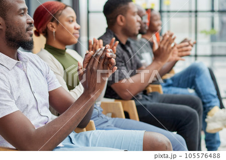 Group of men and women sit in a row and applaud a man who puts forward an idea or says something. Group of men and women sit in a row and applaud a man who puts forward an idea or says something. 105576488
