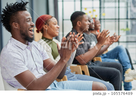 Group of men and women sit in a row and applaud a man who puts forward an idea or says something. Group of men and women sit in a row and applaud a man who puts forward an idea or says something. 105576489