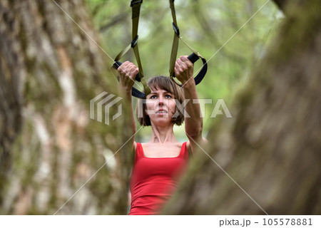 Woman doing arms biceps curl training with trx fitness straps 105578881