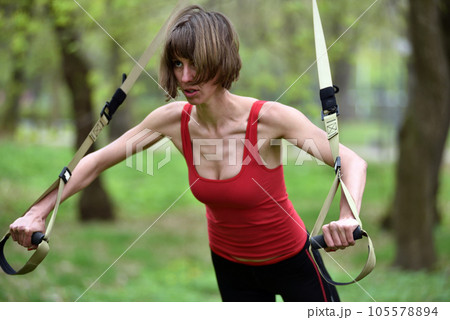 Young woman does suspension training with fitness straps in the outdoors 105578894
