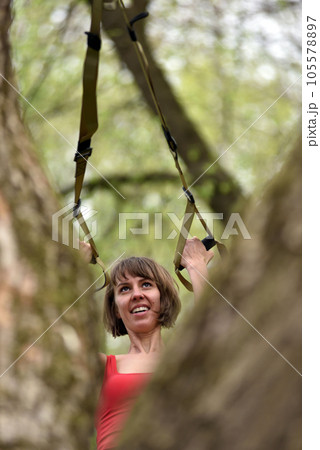 Woman doing arms biceps curl training with trx fitness straps 105578897