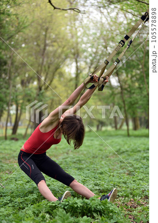 Young attractive woman does body stretching with trx fitness straps 105578898