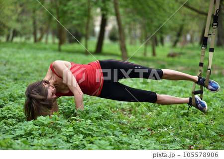 Beautiful young woman doing TRX exercise with suspension trainer sling in the outdoors 105578906