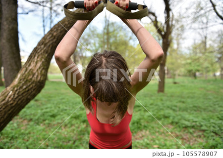 Young attractive woman does body stretching with trx fitness straps 105578907
