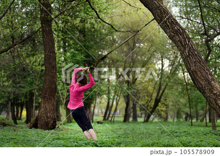 Young attractive woman does body stretching with trx fitness straps 105578909