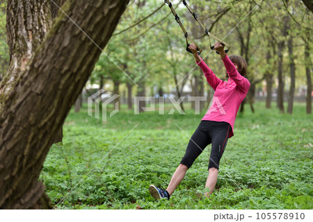 Woman doing arms biceps curl training with trx fitness straps 105578910