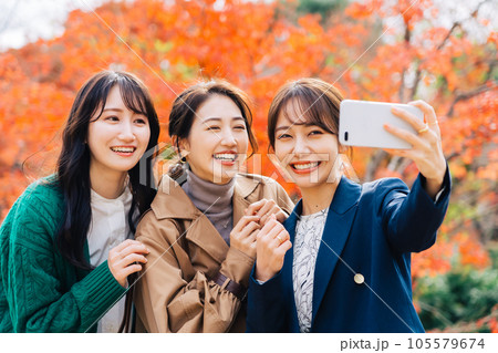 紅葉バックにスマホで写真を撮る女性3人組 紅葉バックにスマホで写真を撮る女性3人組 105579674