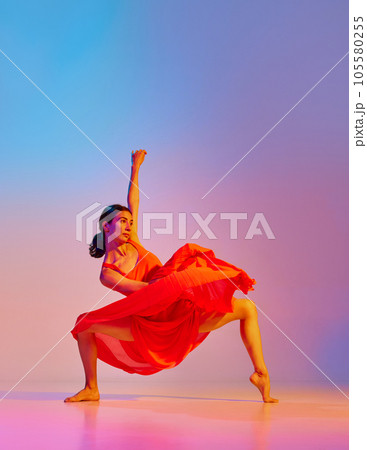 Classic and modern. Elegant young woman dancing contemp in dress against gradient multicolor background in neon light 105580255