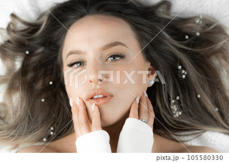 A beautiful woman model looks close-up at the camera. Facial skin rejuvenation in a beauty salon. Skin and face care. Natural cosmetics and makeup. Wrinkle smoothing . Charming look A beautiful woman model looks close-up at the camera. Facial skin rejuvenation in a beauty salon. Skin and face care. Natural cosmetics and makeup. Wrinkle smoothing . Charming look 105580330