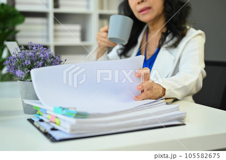 Select focus on hand of senior businesswoman preparing economic report or presentation at office desk. 105582675