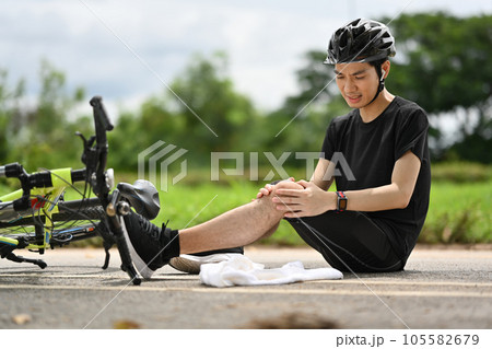 Male cyclist having an accident, falling down from bicycle and injured his knee. Bicycle accident. Male cyclist having an accident, falling down from bicycle and injured his knee. Bicycle accident. 105582679