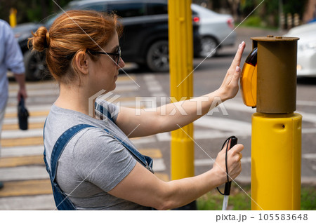 Blind woman pressing a button for a traffic light.  105583648