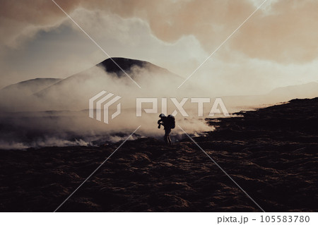 A photographer takes a photo of flowing lava and burning moss under the Icelandic volcano. A photographer takes a photo of flowing lava and burning moss under the Icelandic volcano. 105583780