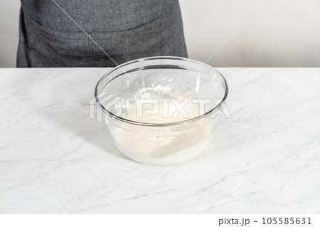 Mixing ingredients in a large glass mixing bowl to make the cream cheese glaze. 105585631