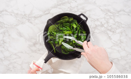 Flat lay. Step by step. Heating cast iron skillet over the stove to prepare spinach and ham frittata. Flat lay. Step by step. Heating cast iron skillet over the stove to prepare spinach and ham frittata. 105586038