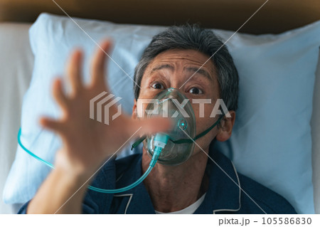 酸素マスクをつけて苦しむシニア男性 105586830