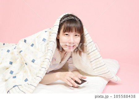 パジャマ姿でスマホを操作する女性 パジャマ姿でスマホを操作する女性 105588438