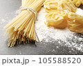 Different dry pasta with flour on grey table 105588520